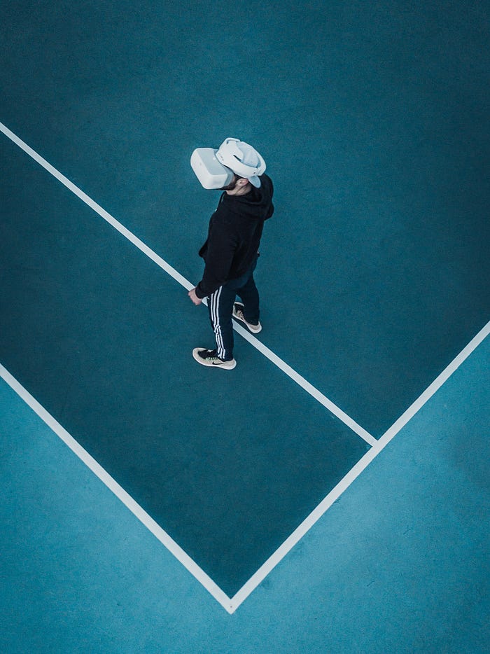 Man in tracksuit wearing virtual reality headset standing on a tennis court